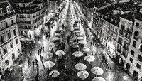 A black and white photo of a city street with many umbrellas and people