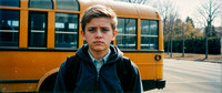 A concerned-looking teenager standing beside a yellow school bus, cinematic look, wide horizontal