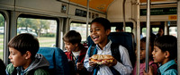 Joyful children eating sandowich and smiling inside a school bus ride back home during daytime,
